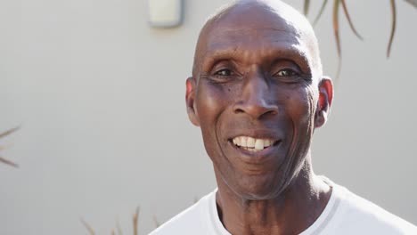 Portrait-of-happy-unaltered-senior-african-american-man-in-front-of-wall-and-plants,-slow-motion