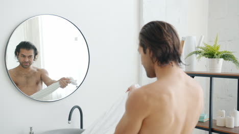 man drying himself with a towel in a modern bathroom
