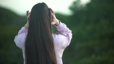 medium shot of a girl moving her silky smooth hair around in nature