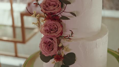 close up of floral cake decoration with pastel pink roses and greenery