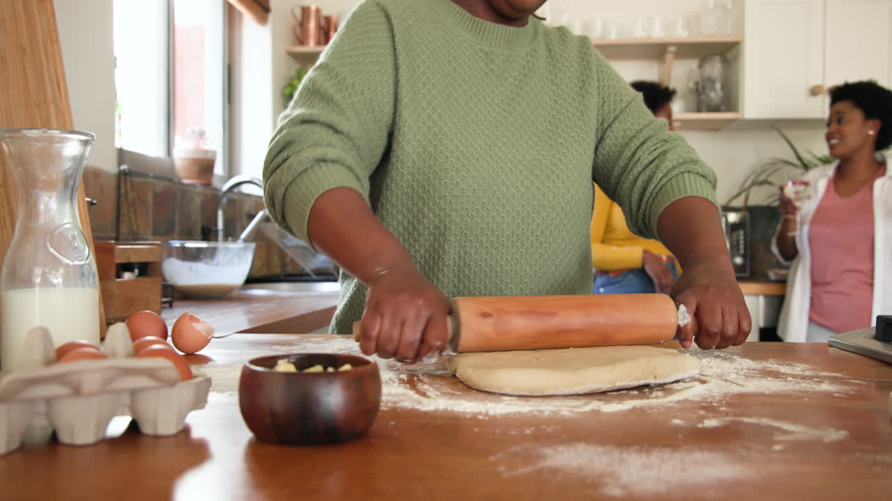 Abrindo massa na cozinha, mulher preparando refeição com amigos.