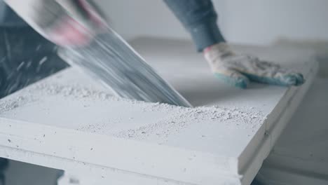 worker in gloves holds big saw and cuts grey board on stand