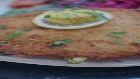 close-up of a crispy breaded cutlet with lemon and parsley