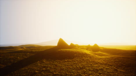 sunset over a grassy field with hills in the distance