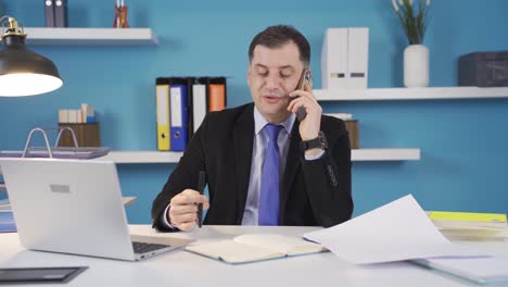 Happy-businessman-talking-on-phone-while-at-work.