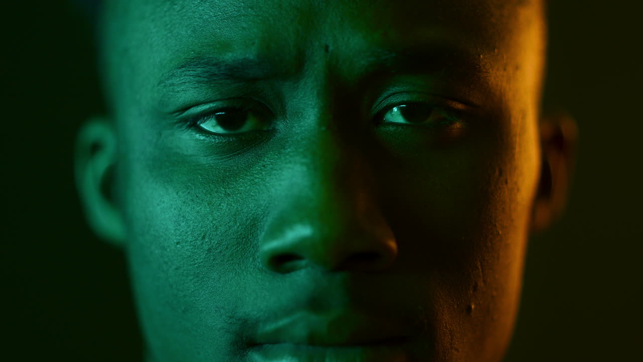 Close-up portrait of a man with green and orange lighting