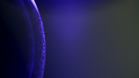 macro disparo de pequeñas partículas que se mueven en sentido contrario a las agujas del reloj en una esfera brillante púrpura