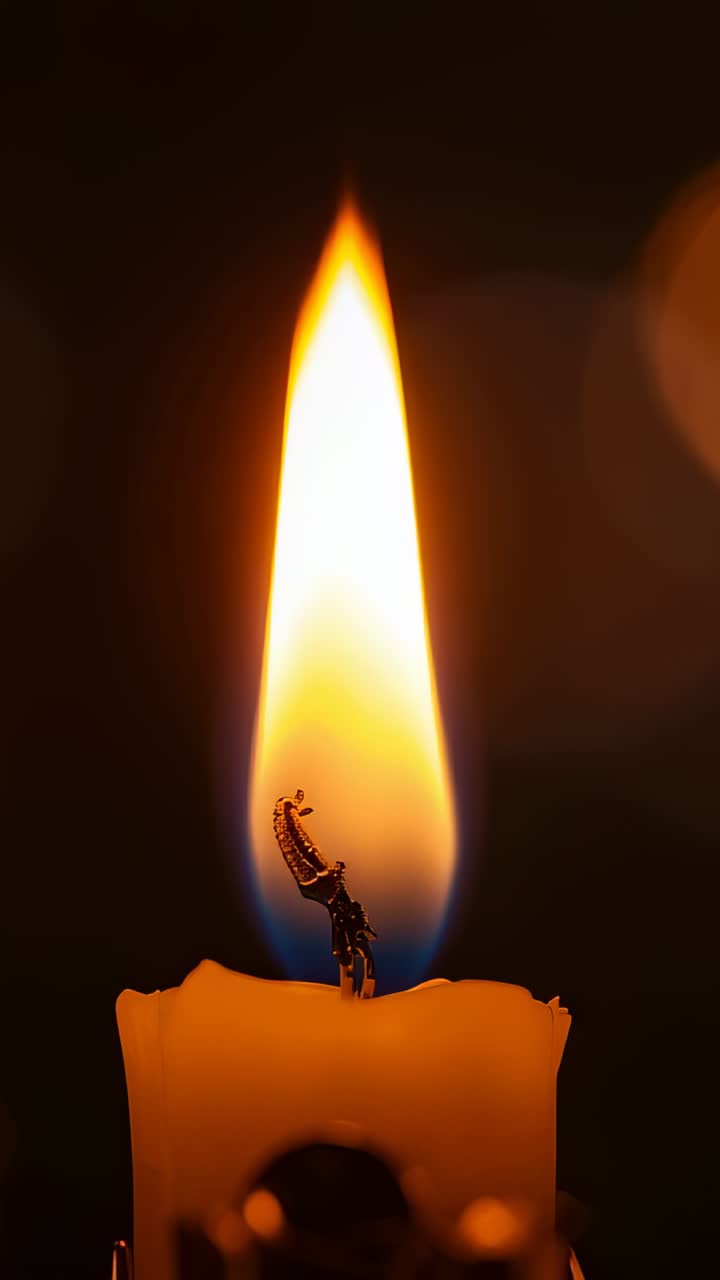 Vertical video: Flickering candle flame on burnt wick dancing in dark room by breeze, wax drips