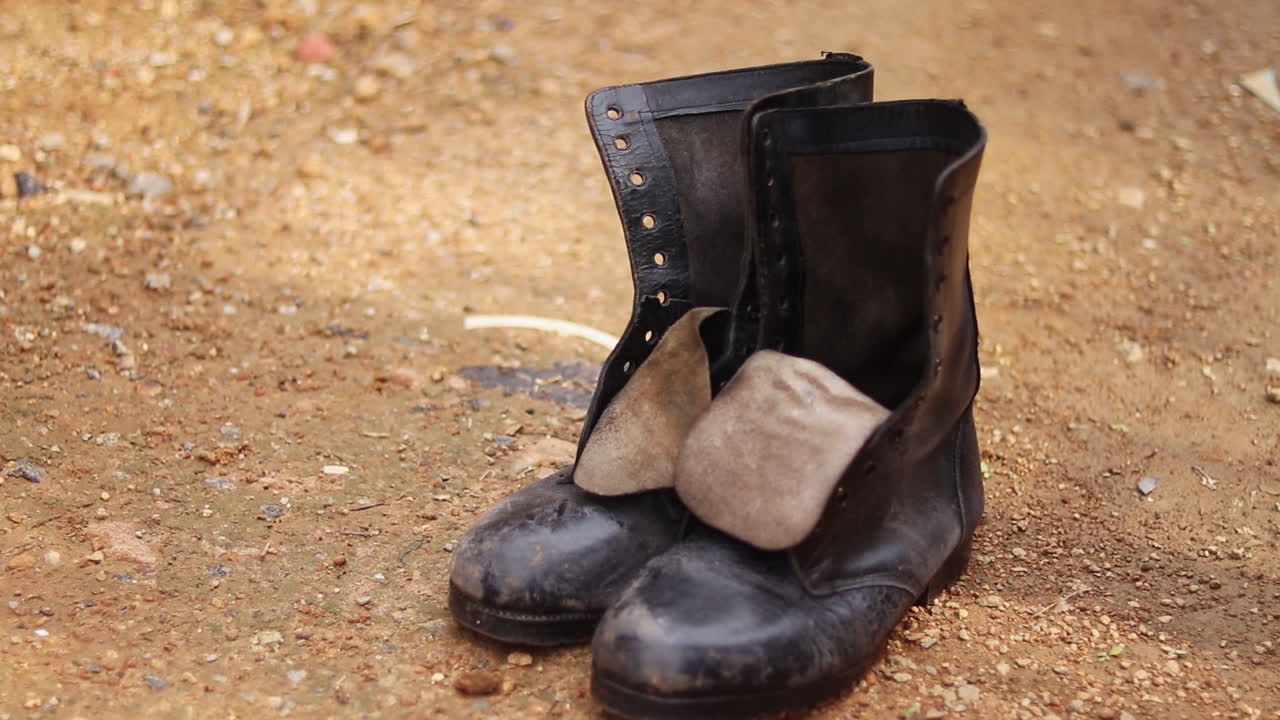 Damaged and worn boots being dropped on the ground