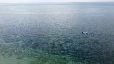 A-local-traditional-Timorese-fishing-and-transport-motorboat-travelling-over-coral-reefs-on-Atauro-Island,-Timor-Leste,-Southeast-Asia