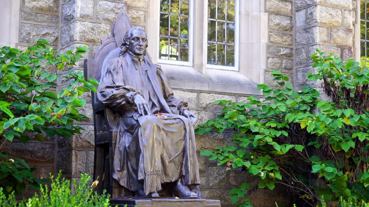 고딕 양식의 창문 앞과 단풍으로 둘러싸인 윌리엄 화이트 주교의 동상