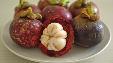 frutas frescas de mangostán maduras en un plato blanco