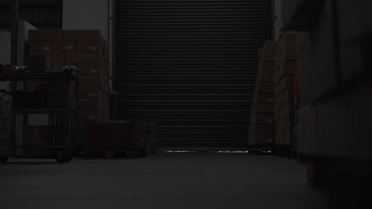 Inside view of a factory roller door opening with an employee and a truck on the other side