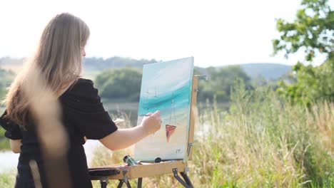 at sunlight young artist painting with oil paint picture on canvas hold brush and palette in light - at sunlight young artist painting with oil paint picture on canvas hold brush and palette in light art studio. workspace. creative