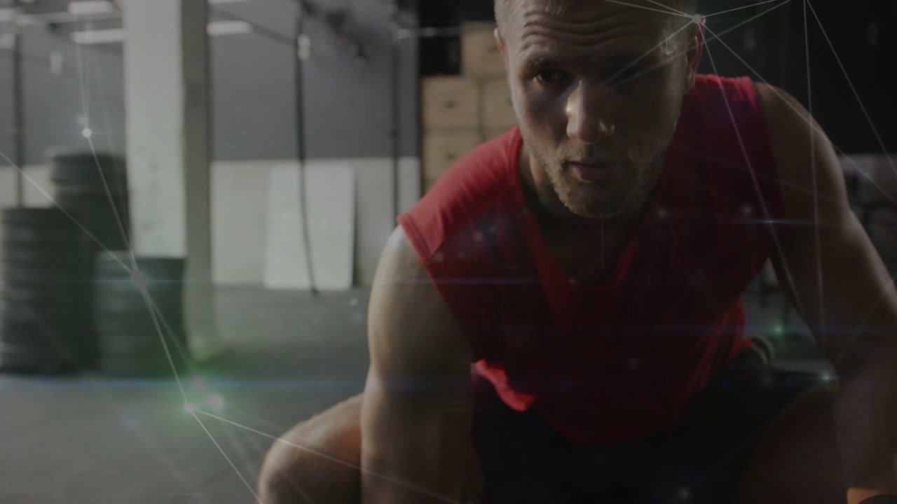 Seated man gripping dumbbell and performing seated curl in gym, overlay mapping muscle activation