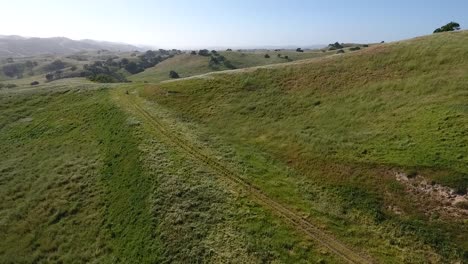 aerial of atv speeding by green rolling hills in santa barbara county