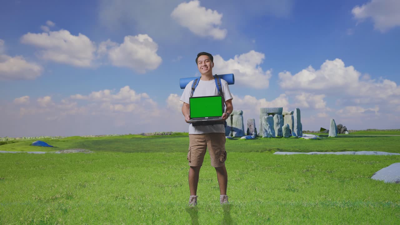 Full Body Of Asian Male Hiker With Mountaineering Backpack Smiling And Showing Mock Up Green Screen Laptop While Traveling In Stonehenge
