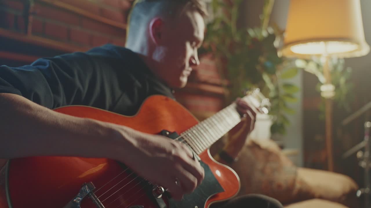 hombre tocando la guitarra acústica en casa