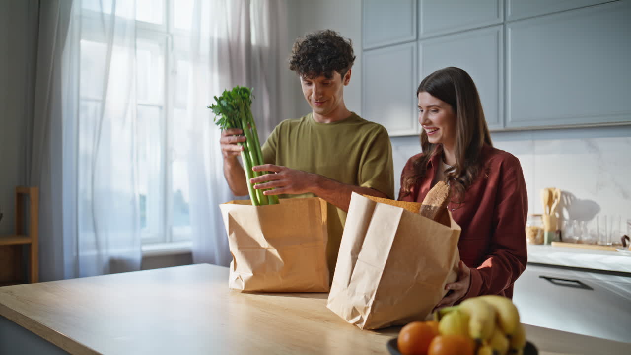 Family couple unpacking groceries kitchen closeup. Pair sharing domestic chores