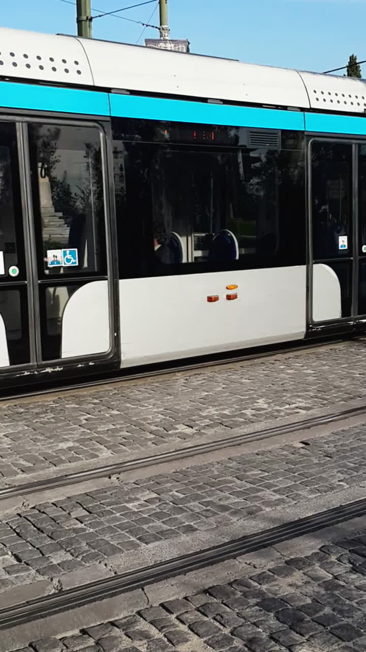 Modern tram in Athens driving along a city street with vehicles nearby, daytime, vertical shot