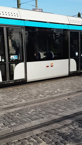 modern tram in athens driving along a city street with vehicles nearby, daytime, vertical shot