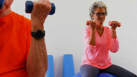 Mixed-race-senior-people-exercising-with-dumbbells-in-the-fitness-studio-4k