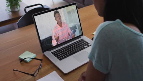 sección media de una mujer afroamericana haciendo una videollamada con un colega masculino en una computadora portátil