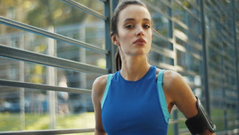 portrait of a pretty sporty woman looking and smiling at the camera while standing at outdoor court on a summer day