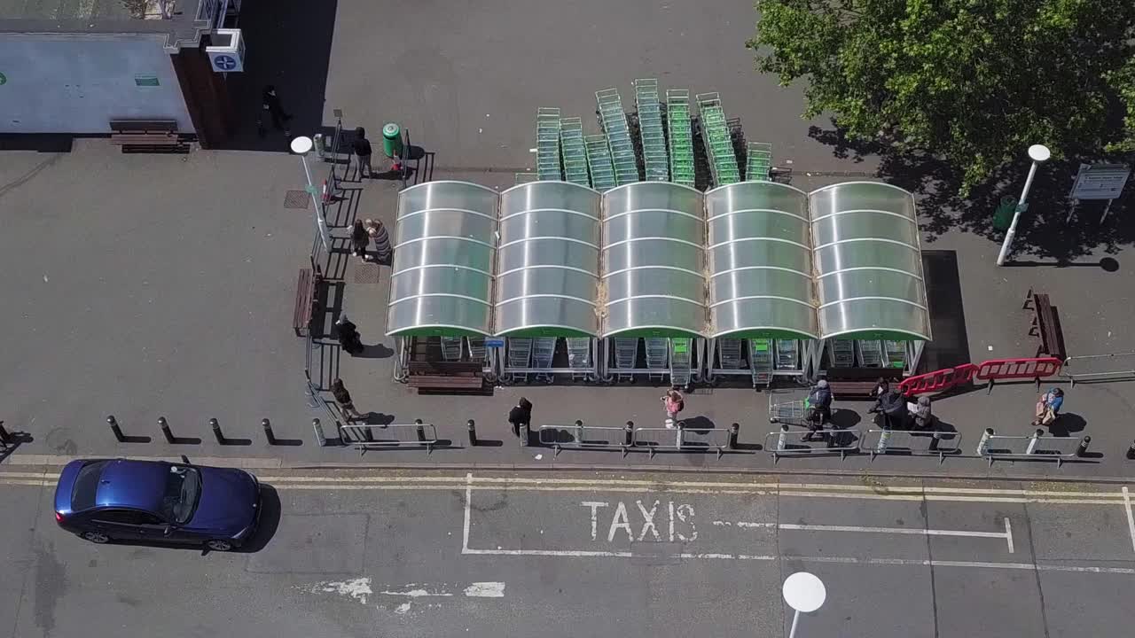Aerial drone view of people getting in the line for the supermarket shopping queue while keeping their social distance from each other and obeying the rules for the pandemic