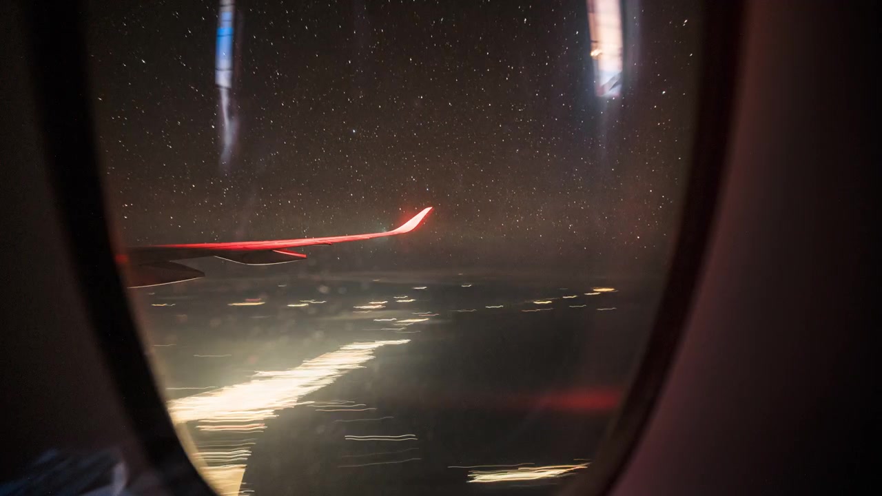 Vista di un cielo notturno stellato e delle luci della città sottostanti, ripresa dal finestrino di un aereo. Ideale per progetti a tema viaggio o aviazione.