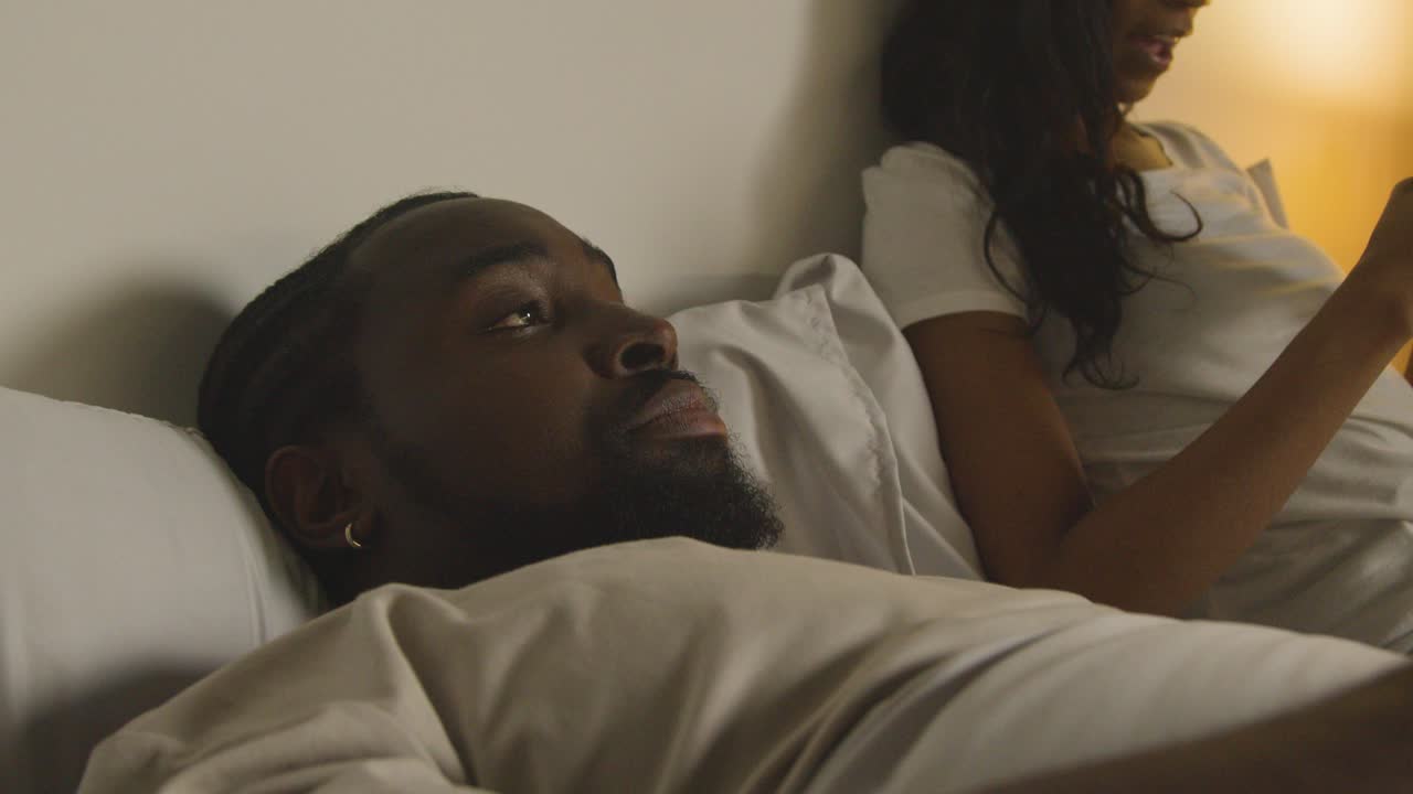 pareja con problemas de relación en casa por la noche acostada en la cama con una mujer mirando teléfonos móviles