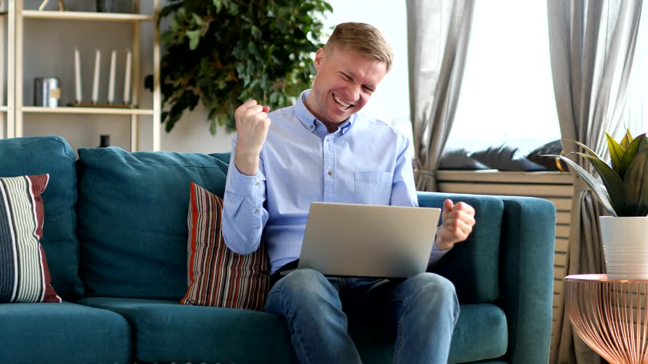 성공에 흥분한 중년 남성, 노트북에서 일하고