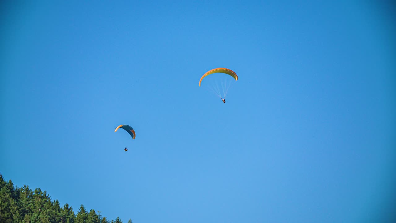 두 명의 패러글라이더가 하늘에서 부드럽게 기동하는 모습은 익스트림 스포츠 모험 같아요.