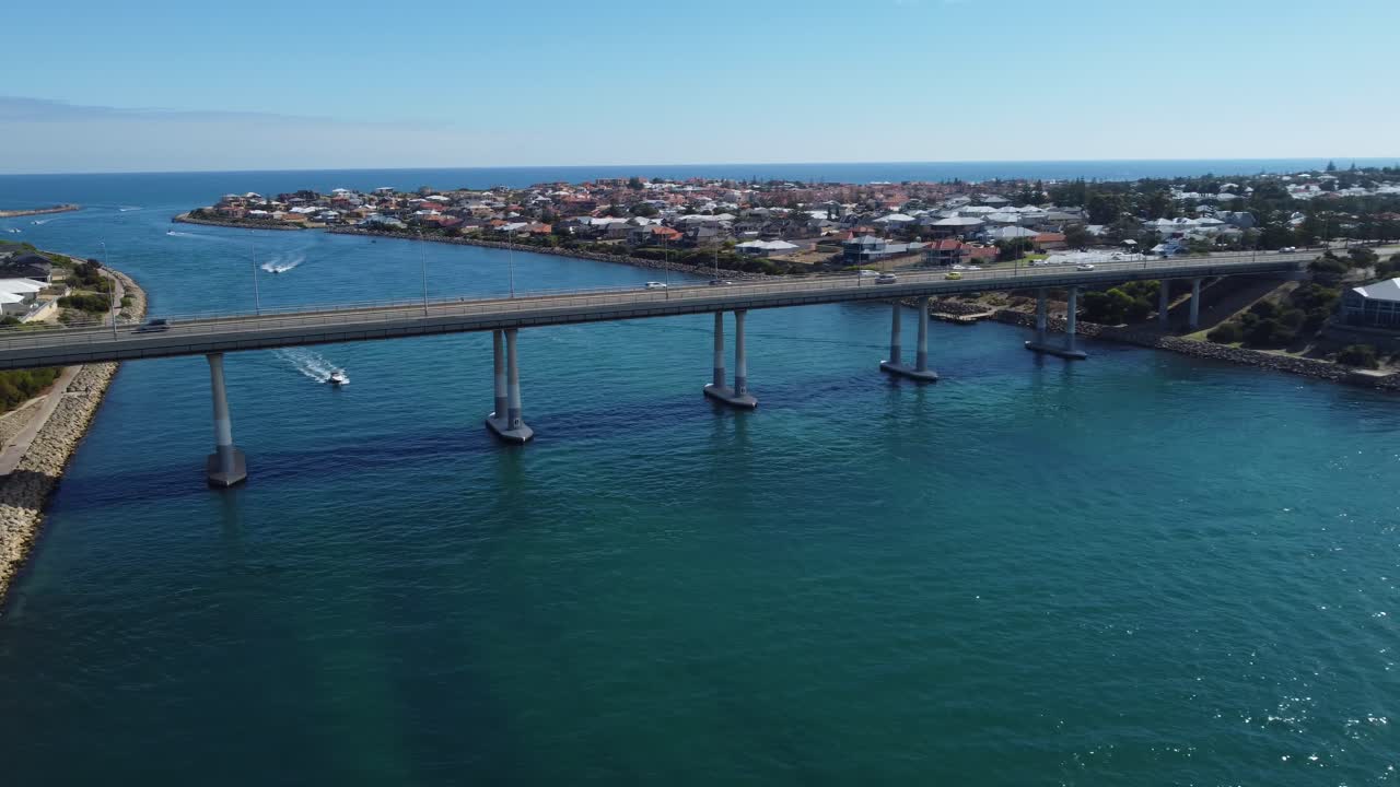 주택을 배경으로 물 위에 매달린 다리 위를 운전하는 공중 추적 차량