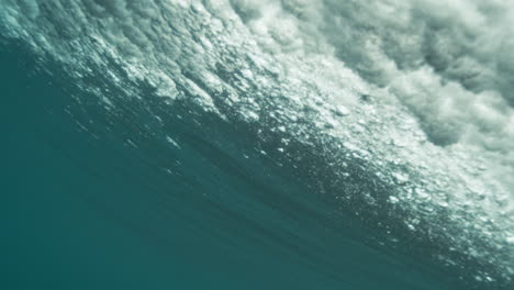 Slow motion of underside of ocean wave, smooth textures and filtered light from below