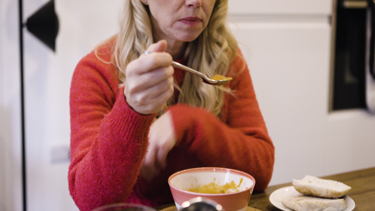 A woman is eating soup
