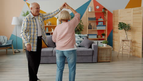 una pareja de mayores bailando en casa.