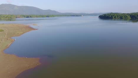 calm waters of rincon dam reservoir, sandy and muddy shores, dominican republic. aerial forward and copy space