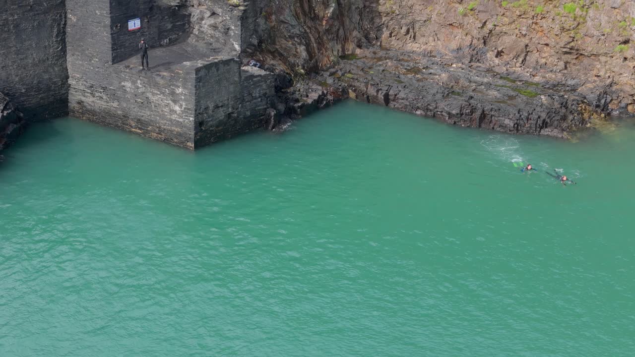 People swimming and prepare to dive in Blue lagoon abandoned quarry turquoise water in Pembrokeshire