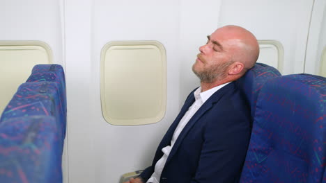 a mature man sleeping on passenger plane airliner relaxing whilst flying