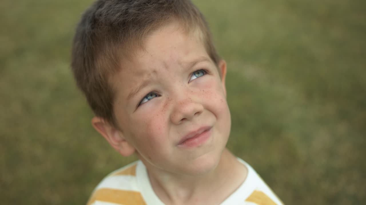 A young boy gazes up at the sky in slow motion, his eyes full of wonder and curiosity. This cinematic footage captures the innocence and imagination of childhood.