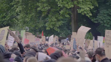 huge racially diverse crowd of protestors raising fists, screaming and holding up signs against racism during a black lives matter protest in the rain in stuttgart germany.