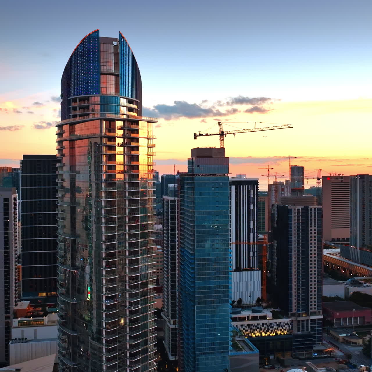 Eye-catching view of Miami downtown with beautiful skyscrapers reflecting sun down light. Drone footage around the modern high-rise buildings.