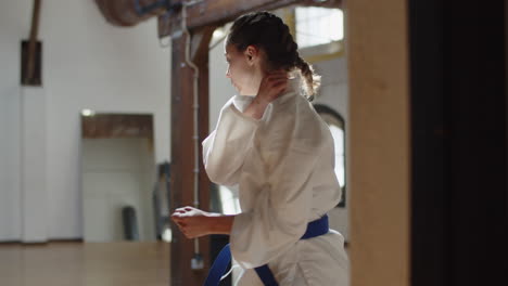 plano medio de karateka arremetiendo y pateando en la sala de práctica