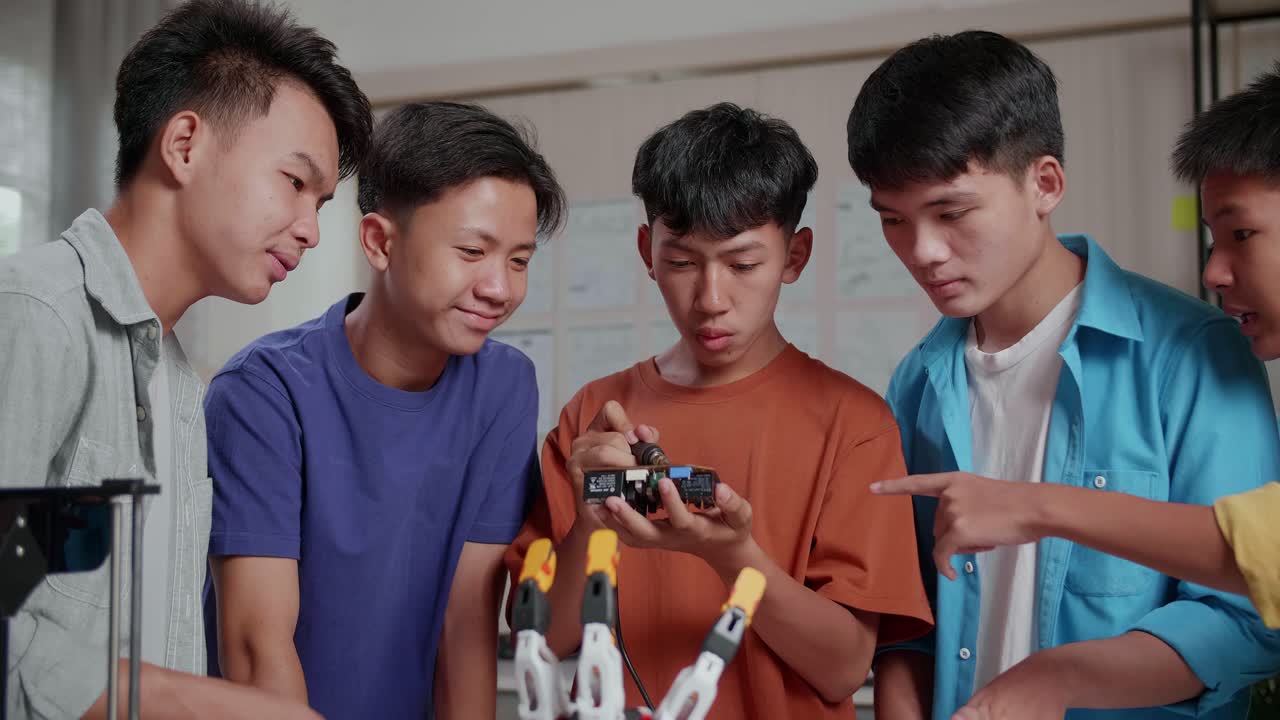 사이보그 손과 3d 프린팅을 가진 젊은 아시아 소년 그룹이 집에서 노트북을 작업하는 동안 회로판을 고치고 있습니다.