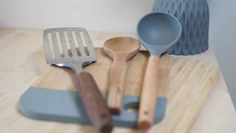 a wooden spoon, a spatula and a ladle on a cutting board