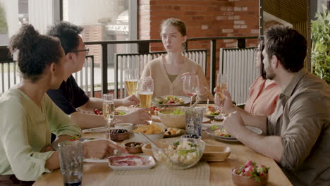 una joven le cuenta una historia a su grupo multicultural de amigos en una cena