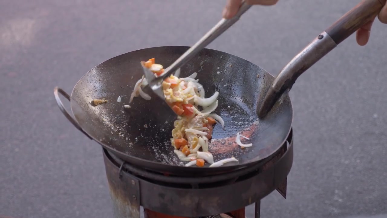 Streetfood-Verkäufer brät Zutaten in einem traditionellen Wok entlang der Charoen Krung Road in Bangkok, Thailand.
