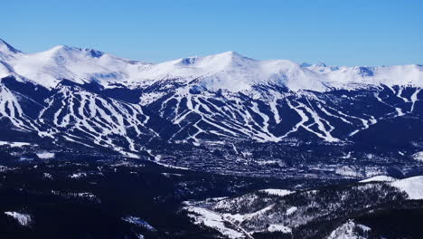 Sunny-winter-morning-blue-sky-Breckenridge-Ski-resort-town-Vail-Epic-Ikon-Pass-aerial-drone-landscape-ski-trail-runs-Summit-County-Tiger-fork-road-Tenmile-peaks-Rocky-Mountains-pan-left