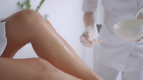 use un palo para aplicar un gel hidratante en las piernas del cliente antes de la depilación láser en las piernas. el médico prepara sus piernas para la depilación láser en un salón de belleza